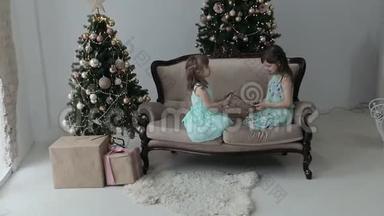 两个女孩坐在房子的地板上，拿着圣诞礼物和一个花环。 女孩玩花环
